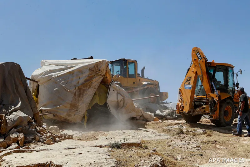 An Israeli bulldozer demolishes sheds belonging to Palestinians near the West Bank village of Yatta, south of Hebron June 19, 2016. Photo by Wisam Hashlamoun