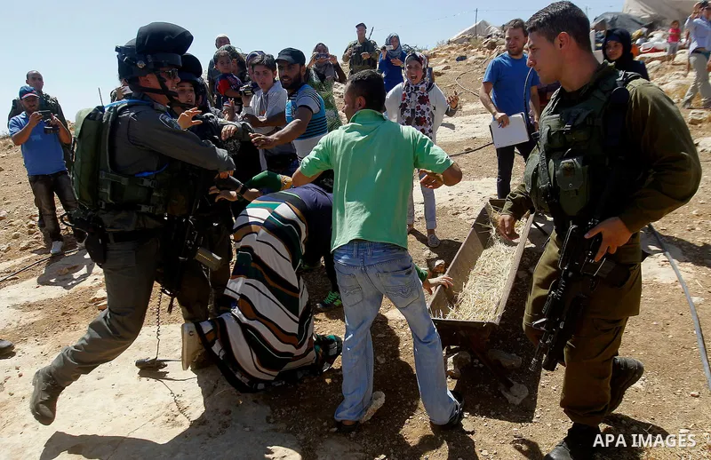 Palestinians scuffle with an Israeli border policeman as Israeli troops demolish sheds belonging to Palestinians near the West Bank village of Yatta, south of Hebron June 19, 2016. Photo by Wisam Hashlamoun