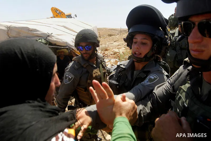 A Palestinian women scuffles with an Israeli border policeman as Israeli troops demolish sheds belonging to Palestinians near the West Bank village of Yatta, south of Hebron June 19, 2016. Photo by Wisam Hashlamoun