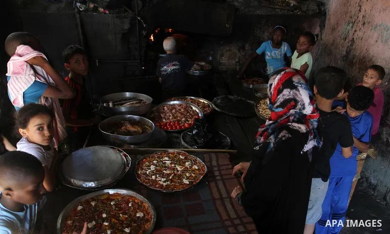 Palestinians wait as they cook their foods in a traditional mud oven during the holy fasting month of Ramadan, in Rafah in the southern Gaza Strip on June 19, 2016. Ramadan is sacred to Muslims because it is during that...