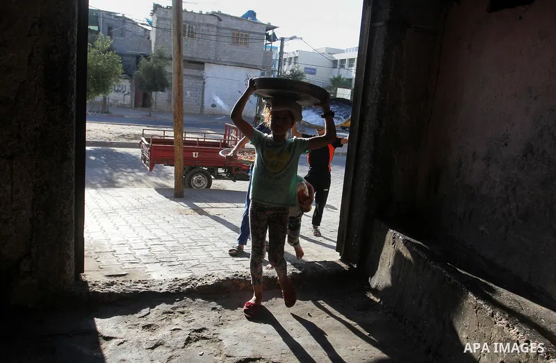 Palestinians wait as they cook their foods in a traditional mud oven during the holy fasting month of Ramadan, in Rafah in the southern Gaza Strip on June 19, 2016. Ramadan is sacred to Muslims because it is during that...