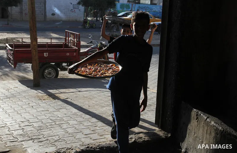Palestinians wait as they cook their foods in a traditional mud oven during the holy fasting month of Ramadan, in Rafah in the southern Gaza Strip on June 19, 2016. Ramadan is sacred to Muslims because it is during that...
