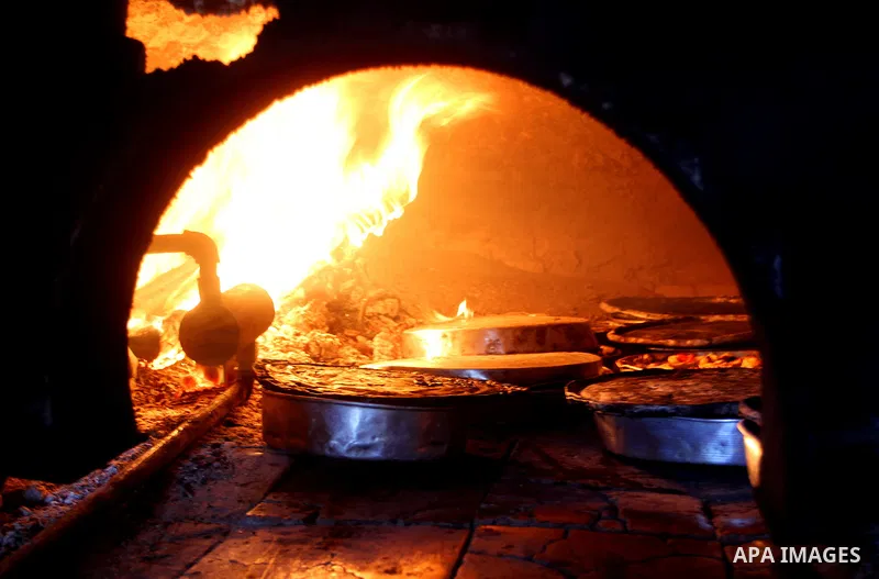 A Palestinian man cooks foods in a traditional mud oven during the holy fasting month of Ramadan, in Rafah in the southern Gaza Strip on June 19, 2016. Ramadan is sacred to Muslims because it is during that month that tr...