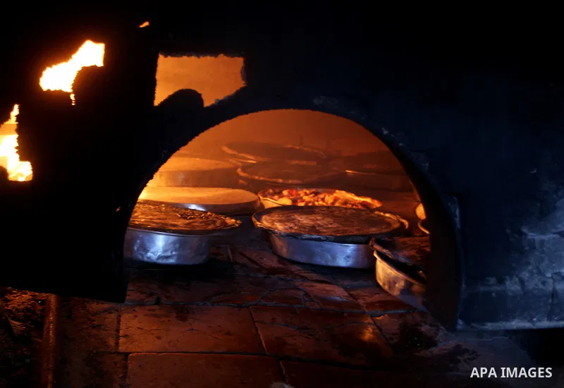 A Palestinian man cooks foods in a traditional mud oven during the holy fasting month of Ramadan, in Rafah in the southern Gaza Strip on June 19, 2016. Ramadan is sacred to Muslims because it is during that month that tr...