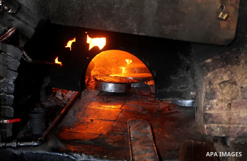 A Palestinian man cooks foods in a traditional mud oven during the holy fasting month of Ramadan, in Rafah in the southern Gaza Strip on June 19, 2016. Ramadan is sacred to Muslims because it is during that month that tr...