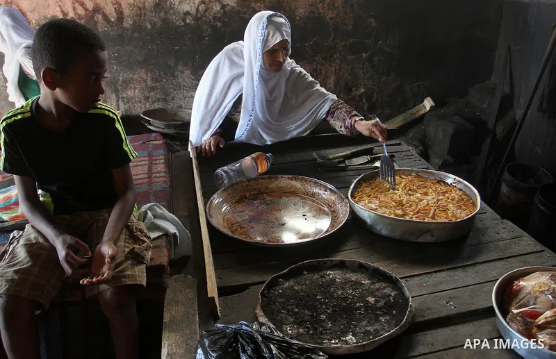 Palestinians wait as they cook their foods in a traditional mud oven during the holy fasting month of Ramadan, in Rafah in the southern Gaza Strip on June 19, 2016. Ramadan is sacred to Muslims because it is during that...
