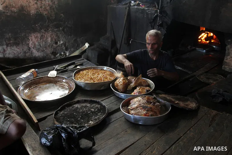 A Palestinian man cooks foods in a traditional mud oven during the holy fasting month of Ramadan, in Rafah in the southern Gaza Strip on June 19, 2016. Ramadan is sacred to Muslims because it is during that month that tr...