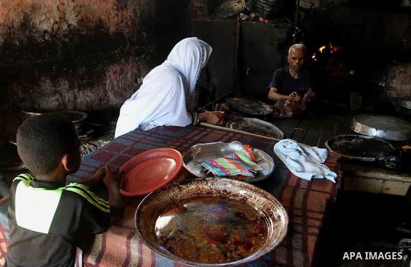 A Palestinian man cooks foods in a traditional mud oven during the holy fasting month of Ramadan, in Rafah in the southern Gaza Strip on June 19, 2016. Ramadan is sacred to Muslims because it is during that month that tr...