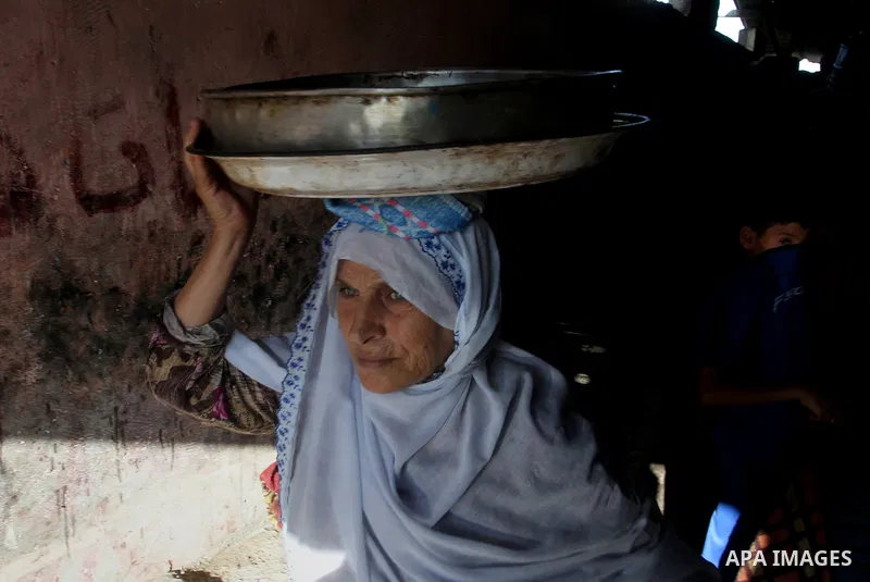 Palestinians wait as they cook their foods in a traditional mud oven during the holy fasting month of Ramadan, in Rafah in the southern Gaza Strip on June 19, 2016. Ramadan is sacred to Muslims because it is during that...