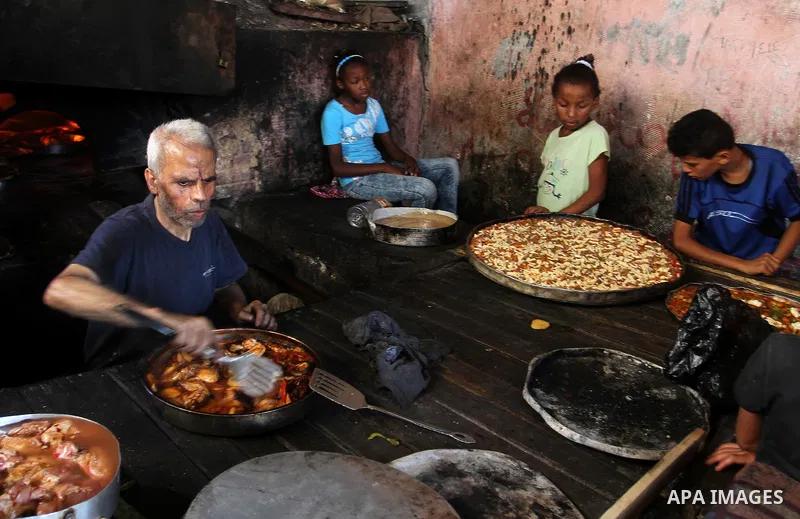 A Palestinian man cooks foods in a traditional mud oven during the holy fasting month of Ramadan, in Rafah in the southern Gaza Strip on June 19, 2016. Ramadan is sacred to Muslims because it is during that month that tr...