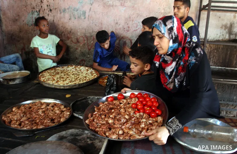 Palestinians wait as they cook their foods in a traditional mud oven during the holy fasting month of Ramadan, in Rafah in the southern Gaza Strip on June 19, 2016. Ramadan is sacred to Muslims because it is during that...