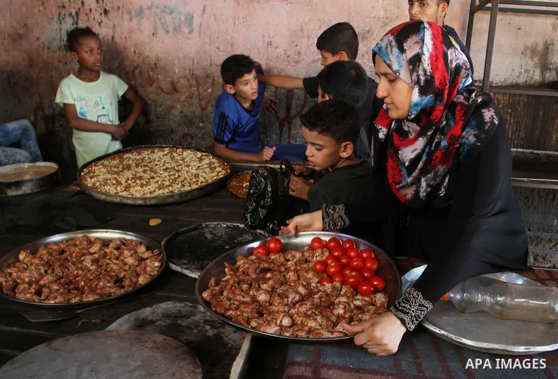 Palestinians wait as they cook their foods in a traditional mud oven during the holy fasting month of Ramadan, in Rafah in the southern Gaza Strip on June 19, 2016. Ramadan is sacred to Muslims because it is during that...