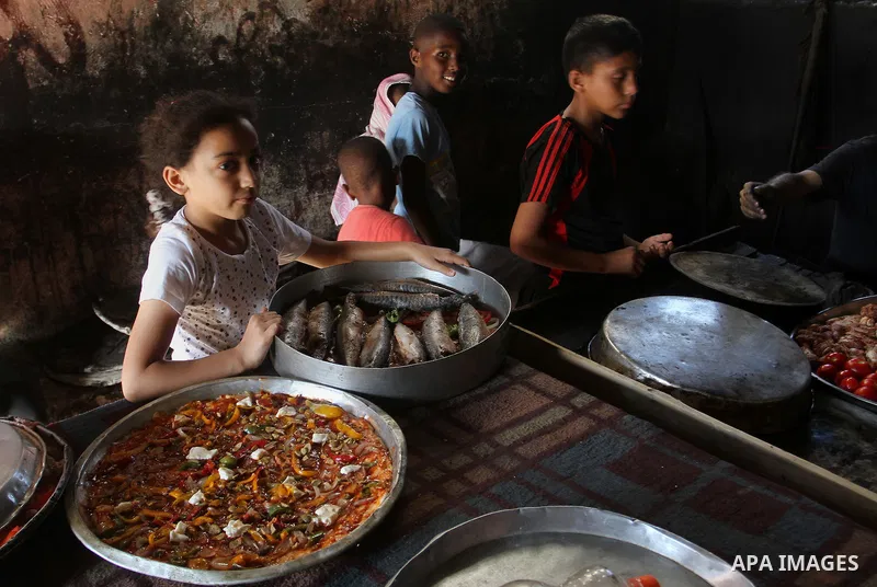 Palestinians wait as they cook their foods in a traditional mud oven during the holy fasting month of Ramadan, in Rafah in the southern Gaza Strip on June 19, 2016. Ramadan is sacred to Muslims because it is during that...