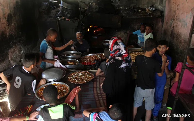 A Palestinian man cooks foods in a traditional mud oven during the holy fasting month of Ramadan, in Rafah in the southern Gaza Strip on June 19, 2016. Ramadan is sacred to Muslims because it is during that month that tr...