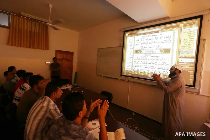 A Palestinian imam uses sign-language to teach the Koran, Islam's holy book, to deaf students at a religion school in Gaza City on June 21 2016, during the Muslim fasting month of Ramadan. Photo by Mohammed Asad