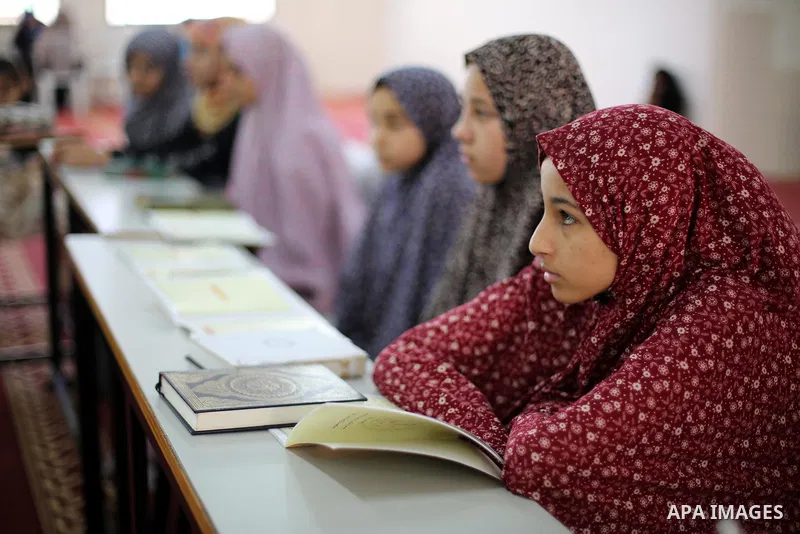 A Palestinian woman teaches young girls the Koran, Islam's holy book, at a religion school in Gaza City on June 21, 2016, during the Muslim fasting month of Ramadan. Photo by Mohammed Asad