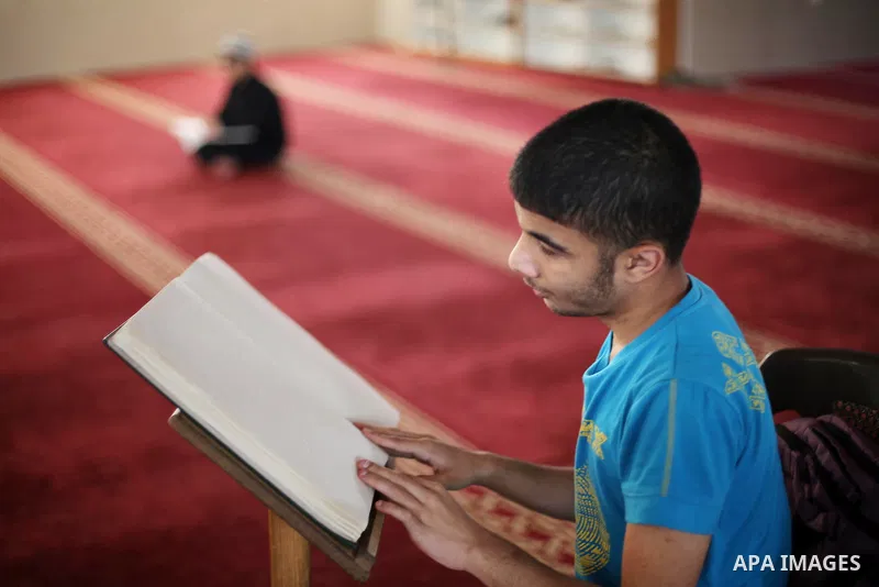 Palestinian blind youths read a copy of the Koran, Islam's holy book, at a religion school in Gaza City on June 21, 2016, during the Muslim fasting month of Ramadan. Photo by Mohammed Asad