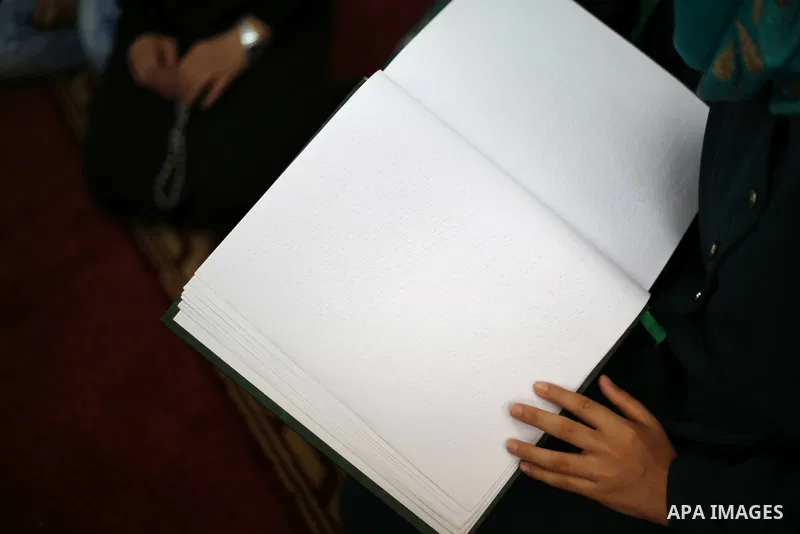 A Palestinian blind girl reads a copy of the Koran, Islam's holy book, at a religion school in Gaza City on June 21, 2016, during the Muslim fasting month of Ramadan. Photo by Mohammed Asad
