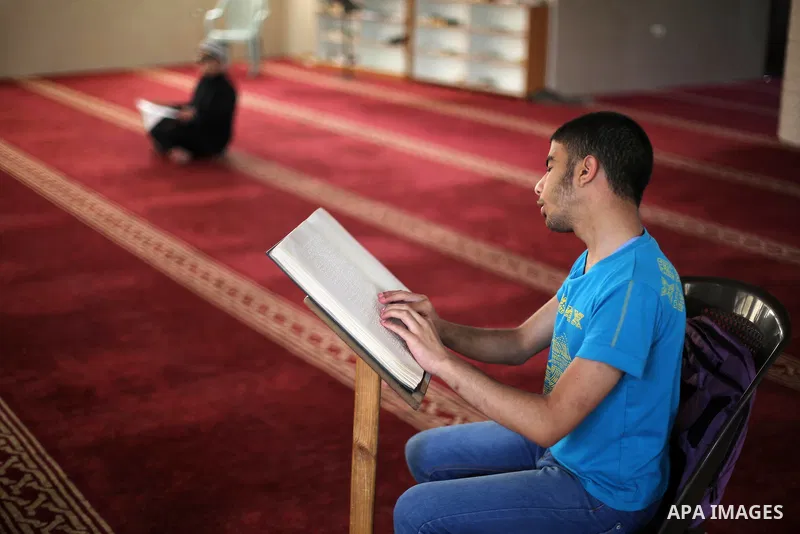 Palestinian blind youths read a copy of the Koran, Islam's holy book, at a religion school in Gaza City on June 21, 2016, during the Muslim fasting month of Ramadan. Photo by Mohammed Asad