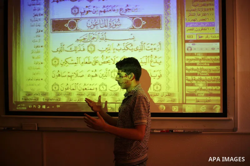 A Palestinian young man uses sign-language to read a projection of the Koran, Islam's holy book, during a class for deaf students at a religion school in Gaza City on June 21, 2016 during the Muslim fasting month of Rama...