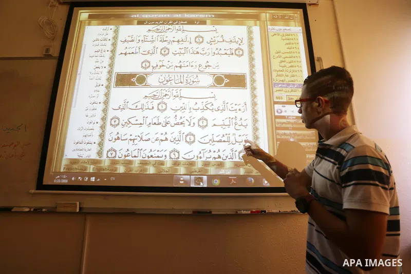A Palestinian young man uses sign-language to read a projection of the Koran, Islam's holy book, during a class for deaf students at a religion school in Gaza City on June 21, 2016 during the Muslim fasting month of Rama...