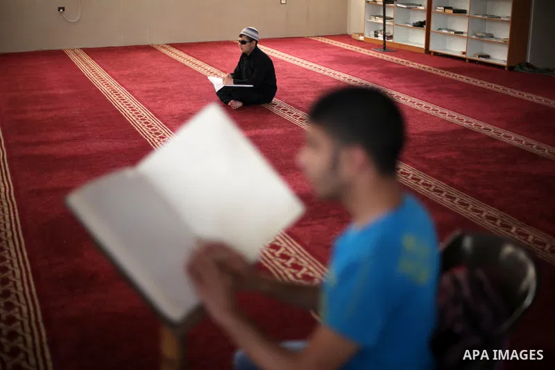 Palestinian blind youths read a copy of the Koran, Islam's holy book, at a religion school in Gaza City on June 21, 2016, during the Muslim fasting month of Ramadan. Photo by Mohammed Asad