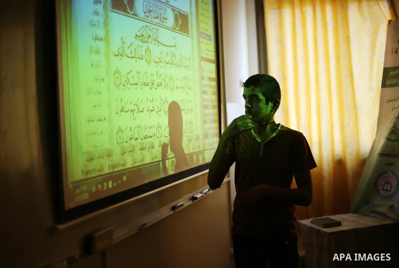 A Palestinian young man uses sign-language to read a projection of the Koran, Islam's holy book, during a class for deaf students at a religion school in Gaza City on June 21, 2016 during the Muslim fasting month of Rama...
