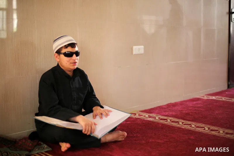 A Palestinian blind youth reads a copy of the Koran, Islam's holy book, at a religion school in Gaza City on June 21, 2016, during the Muslim fasting month of Ramadan. Photo by Mohammed Asad