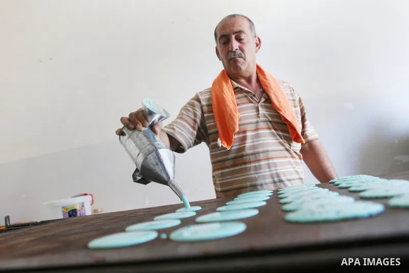 A Palestinian man prepares traditional pancakes known as ''Qatayef" at his shop during the Muslim holy fasting month of Ramadan in the West Bank village of Ein Yabrud near Ramallah on June, 21, 2016. Ramadan is sacred to...