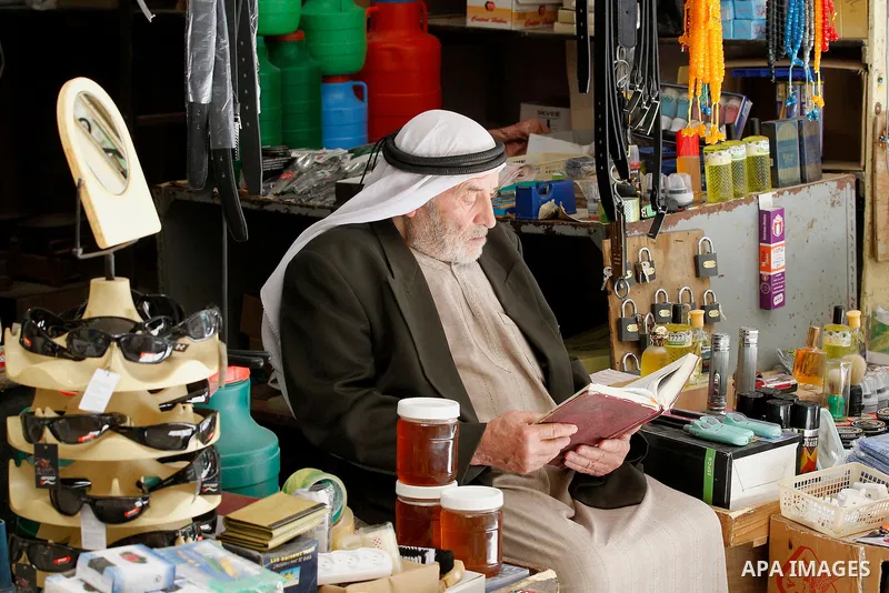 A Palestinian man reads the Koran, Islam's holy book, in front of his shop at market on the holy month of Ramadan at market in the Old City of the West Bank town of Hebron on June 22, 2016. Ramadan is sacred to Muslims b...