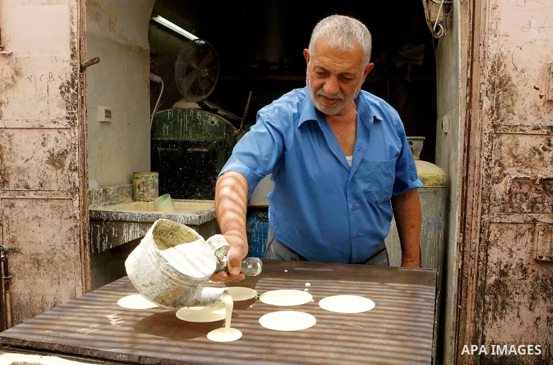 A Palestinian man prepares traditional pancakes known as ''Qatayef'' on the holy month of Ramadan at market in the Old City of the West Bank town of Hebron on June 22, 2016. Ramadan is sacred to Muslims because it is dur...