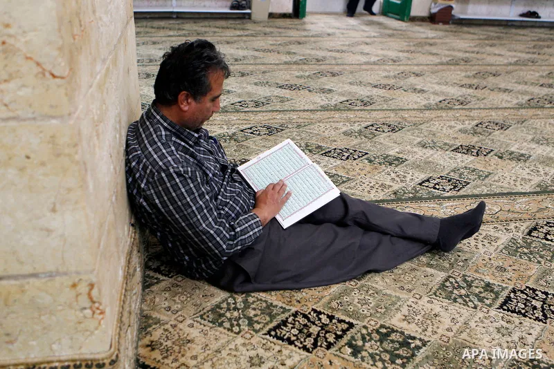 A Palestinian man reads the Koran, Islam's holy book, at al-Qzazeen mosque on the holy month of Ramadan at market in the Old City of the West Bank town of Hebron on June 22, 2016. Ramadan is sacred to Muslims because it...