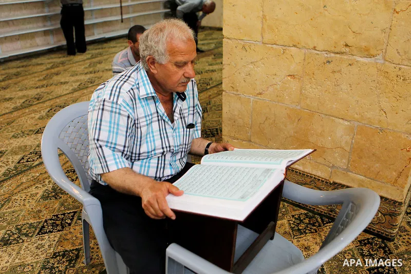 A Palestinian man reads the Koran, Islam's holy book, at al-Qzazeen mosque on the holy month of Ramadan at market in the Old City of the West Bank town of Hebron on June 22, 2016. Ramadan is sacred to Muslims because it...
