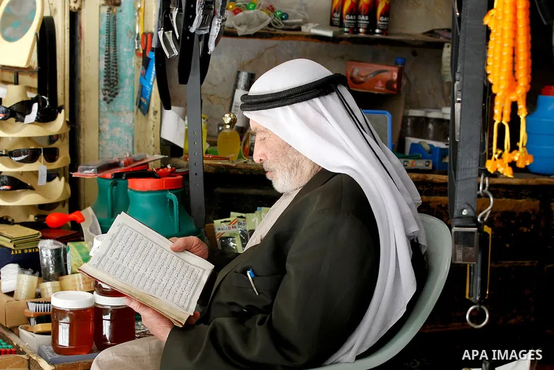 A Palestinian man reads the Koran, Islam's holy book, in front of his shop at market on the holy month of Ramadan at market in the Old City of the West Bank town of Hebron on June 22, 2016. Ramadan is sacred to Muslims b...