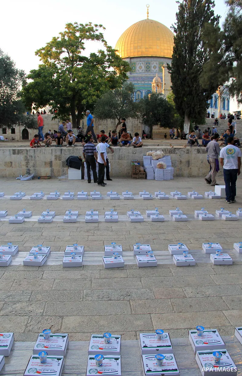 Palestinian muslims prepare to break their fast during the holy fasting month of Ramadan in front of the Dome of the Rock mosque at the al-Aqsa mosque compound, in Jerusalem's old city on June 22, 2016. Ramadan is sacred...