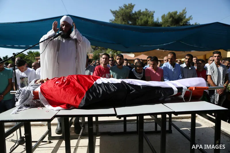 Mourners pray next to the body of Palestinian boy Mahmoud Badran, 15, who was killed by Israeli troops on Tuesday, during his funeral in the village of Beit Ore-Tahta near the West Bank city of Ramallah June 23, 2016. Ph...