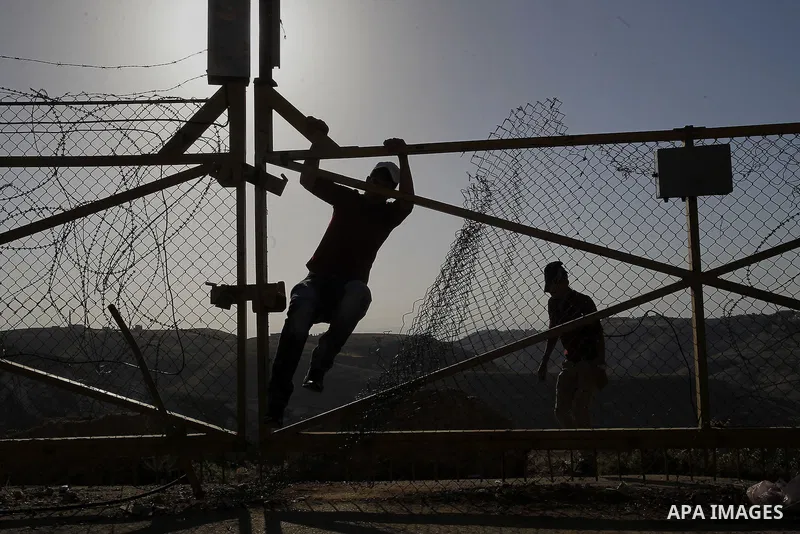 A Palestinian passes through an opening in the Israeli barrier fence as he attempts to make his way to attend the third Friday prayer of the holy fasting month of Ramadan in Jerusalem's al-Aqsa mosque, near the West bank...