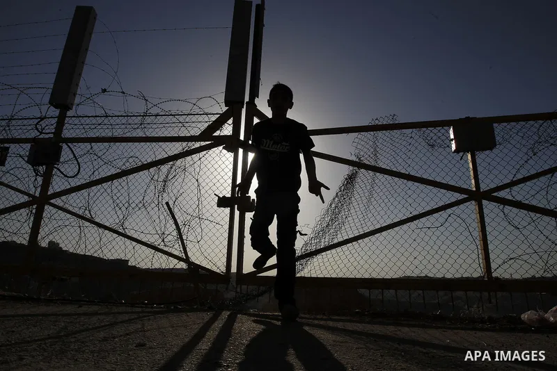 A Palestinian passes through an opening in the Israeli barrier fence as he attempts to make his way to attend the third Friday prayer of the holy fasting month of Ramadan in Jerusalem's al-Aqsa mosque, near the West bank...