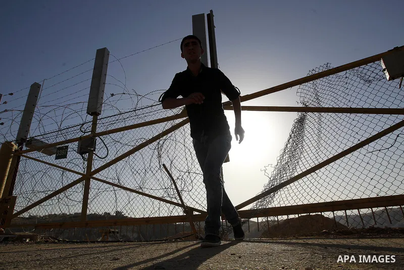 A Palestinian passes through an opening in the Israeli barrier fence as he attempts to make his way to attend the third Friday prayer of the holy fasting month of Ramadan in Jerusalem's al-Aqsa mosque, near the West bank...