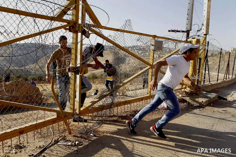 Palestinians pass through an opening in the Israeli barrier fence as they attempt to make their way to attend the third Friday prayer of the holy fasting month of Ramadan in Jerusalem's al-Aqsa mosque, near the West bank...