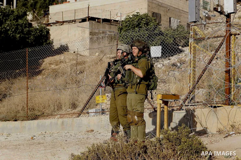 Israeli soldiers stand guard as Palestinian Muslims pass through an opening in the Israeli barrier fence as they attempt to make their way to attend the third Friday prayer of the holy fasting month of Ramadan in Jerusal...
