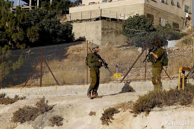 Israeli soldiers stand guard as Palestinian Muslims pass through an opening in the Israeli barrier fence as they attempt to make their way to attend the third Friday prayer of the holy fasting month of Ramadan in Jerusal...