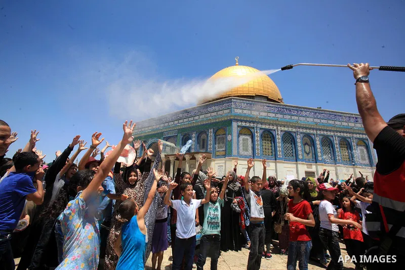 Palestinian men spray water on children to cool them down before prayers on the third Friday of the holy month of Ramadan near the Dome of the Rock, on the compound known to Muslims as Noble Sanctuary and to Jews as Temp...
