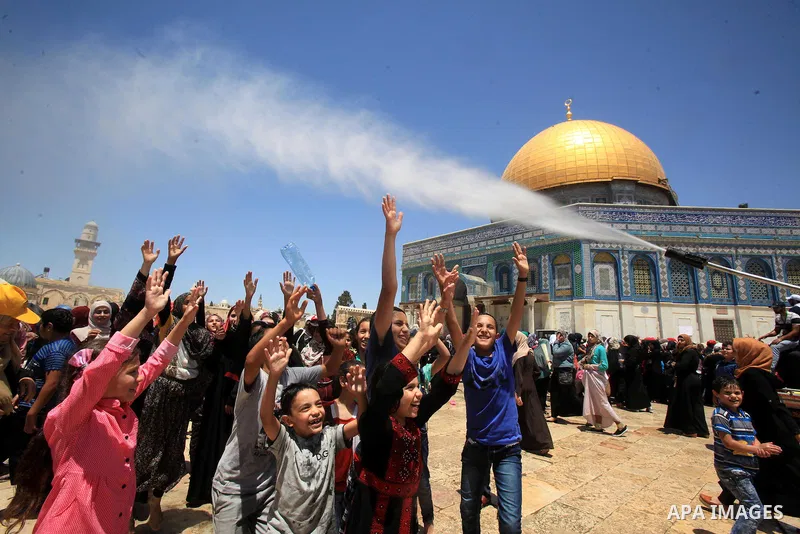 Palestinian men spray water on children to cool them down before prayers on the third Friday of the holy month of Ramadan near the Dome of the Rock, on the compound known to Muslims as Noble Sanctuary and to Jews as Temp...