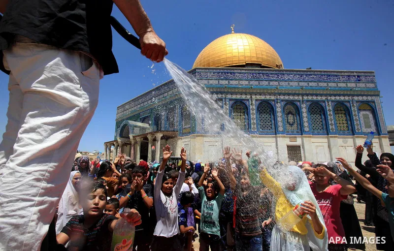 Palestinian men spray water on children to cool them down before prayers on the third Friday of the holy month of Ramadan near the Dome of the Rock, on the compound known to Muslims as Noble Sanctuary and to Jews as Temp...