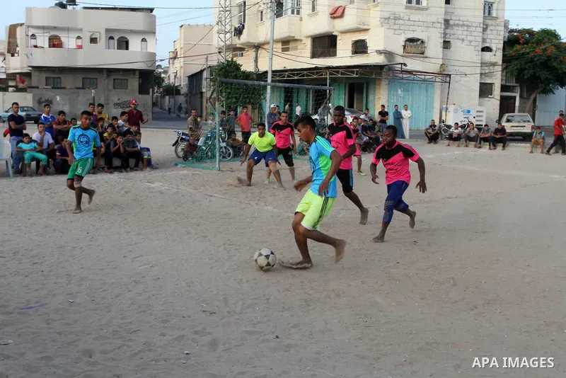Palestinian youths play football match, at a refugee camp in Rafah, in the southern Gaza Strip, during the Muslim holy month of Ramadan on June 25, 2016. Muslims around the world abstain from food, drink and sexual inter...