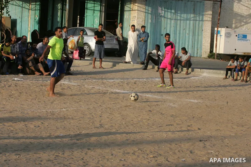 Palestinian youths play football match, at a refugee camp in Rafah, in the southern Gaza Strip, during the Muslim holy month of Ramadan on June 25, 2016. Muslims around the world abstain from food, drink and sexual inter...