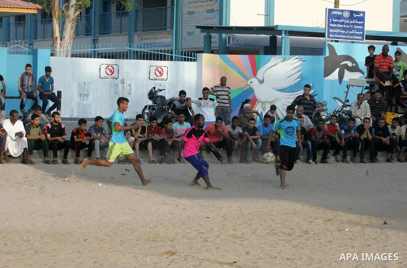 Palestinian youths play football match, at a refugee camp in Rafah, in the southern Gaza Strip, during the Muslim holy month of Ramadan on June 25, 2016. Muslims around the world abstain from food, drink and sexual inter...