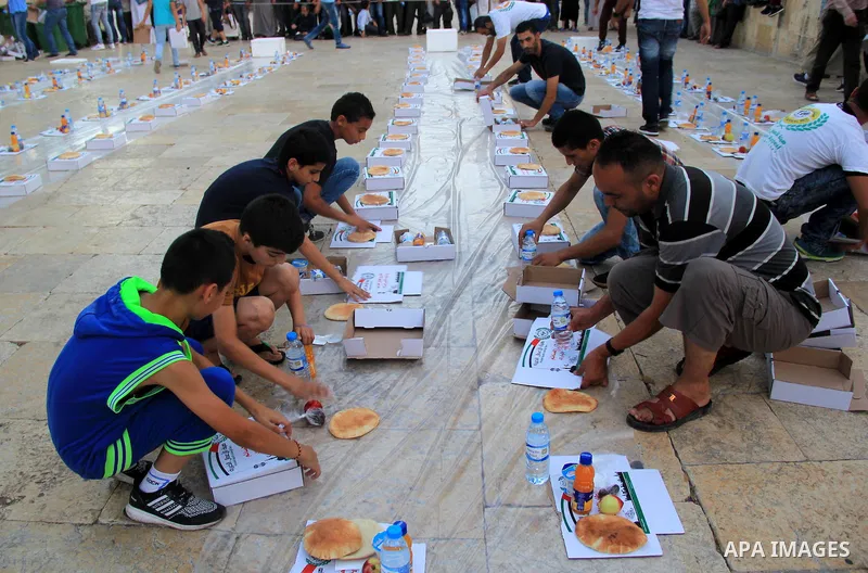 Palestinian muslims prepare to break their fast during the holy fasting month of Ramadan in front of the Dome of the Rock mosque at the al-Aqsa mosque compound, in Jerusalem's old city on June 25, 2016. Ramadan is sacred...