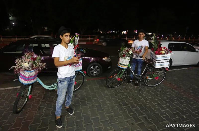 Palestinian youths wander on colorful bicycles and sell flowers at street in Gaza city, on June 26, 2016. Unemployment in the Palestinian enclave of Gaza has risen dramatically to reach around 45 percent, one of the high...
